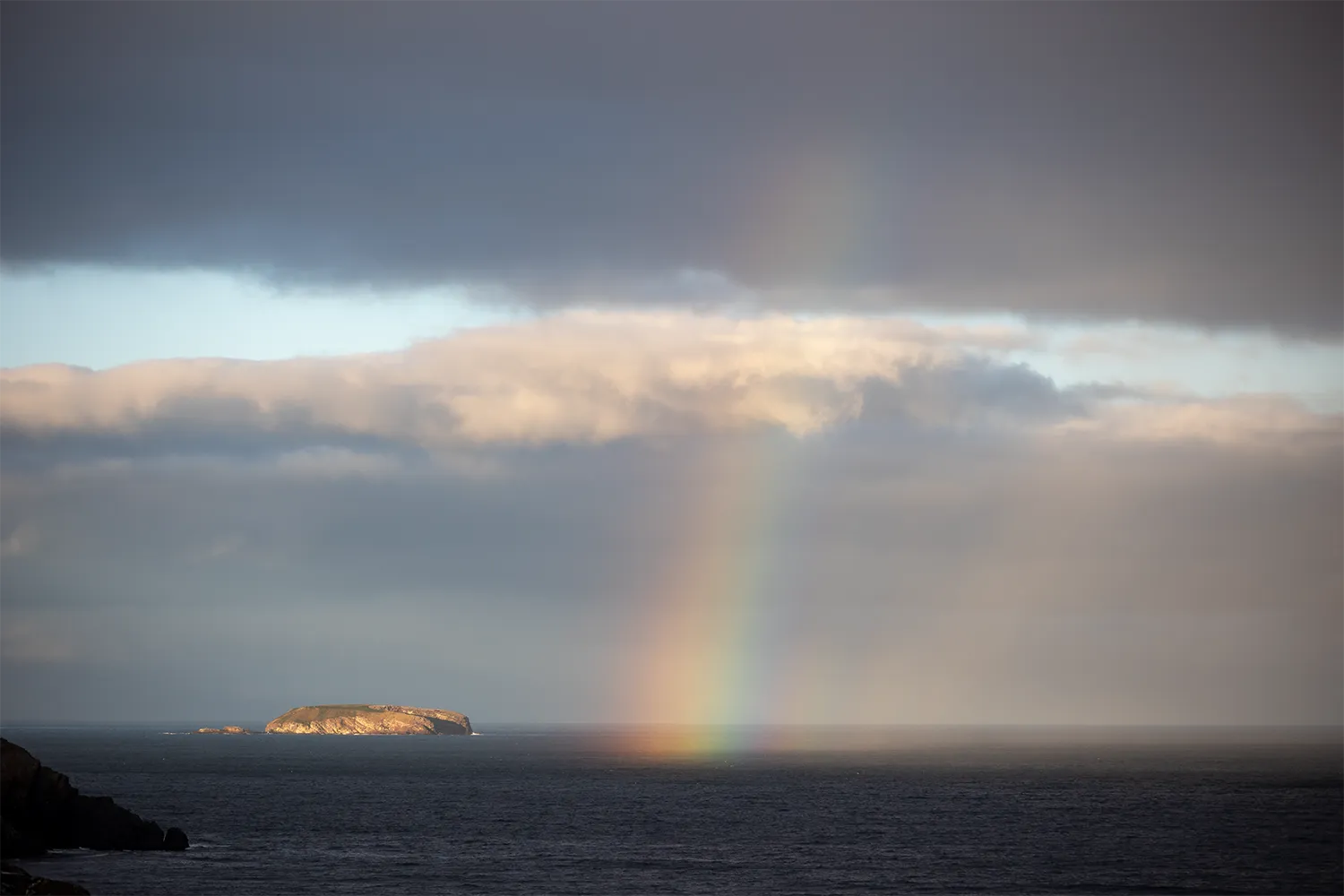 Rainbow descending over an island in Witless Bay Ecological Reserve, Newfoundland